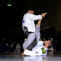 Two Brazilian Jiu-Jitsu practitioners at Creighton MMA engaged in a grappling exchange, with one attempting to pass guard while the other works to control the position from the bottom.