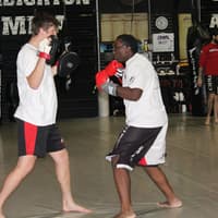 Two martial artists practicing striking drills with focus mitts at Creighton MMA Training Academy.