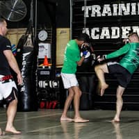 Men practicing kickboxing in a gym setting, demonstrating their techniques and physical fitness in a collaborative atmosphere.