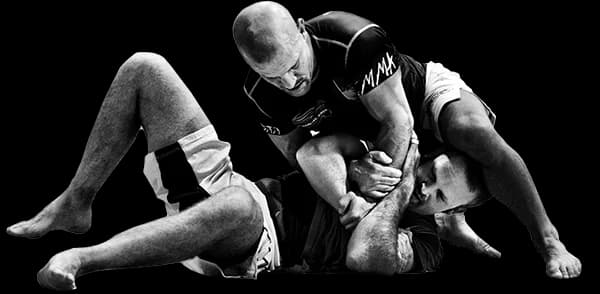 Head instructor Paul Creighton demonstrates a Kimura submission hold from the top position during a Brazilian Jiu-Jitsu training session.